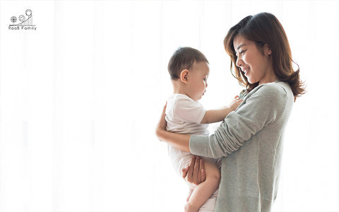 a mother carrying her baby close to her chest